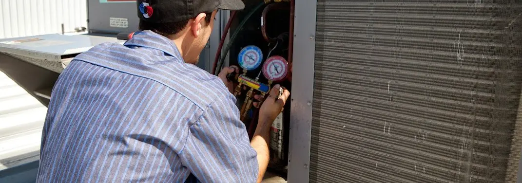 HVAC technician servicing a condenser unit in Hawthorne